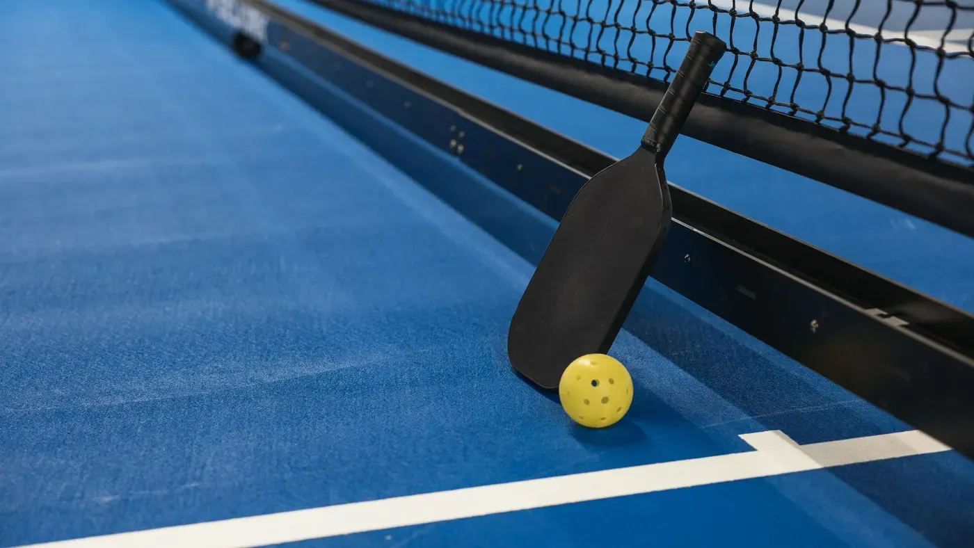 Pickleballracket och boll på en bana
