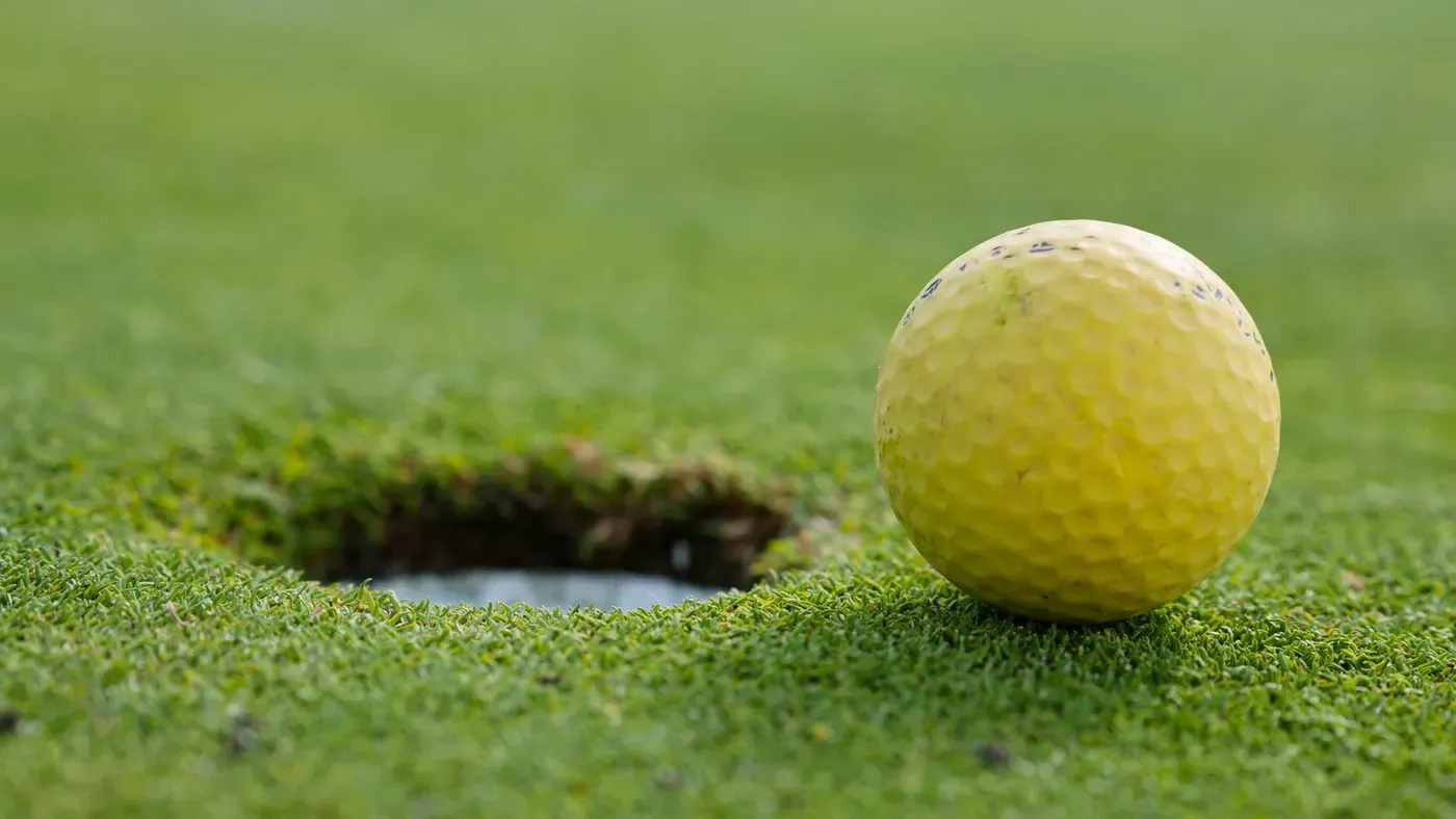Putter och golfboll på green