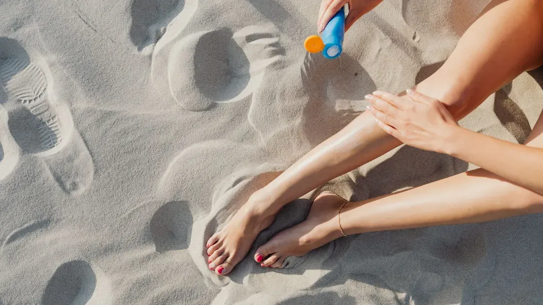 Solkräm och solglasögon på ett strandhandduksunderlag